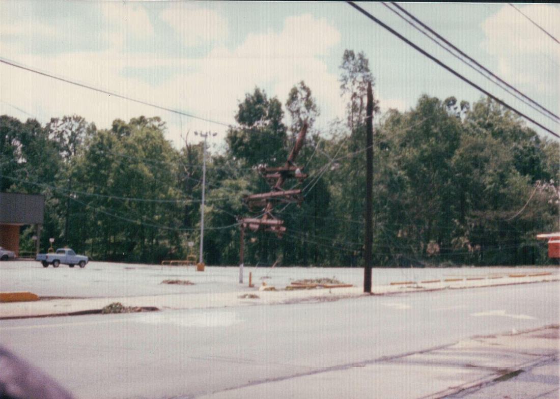 A severely damaged utility pole with hanging power lines